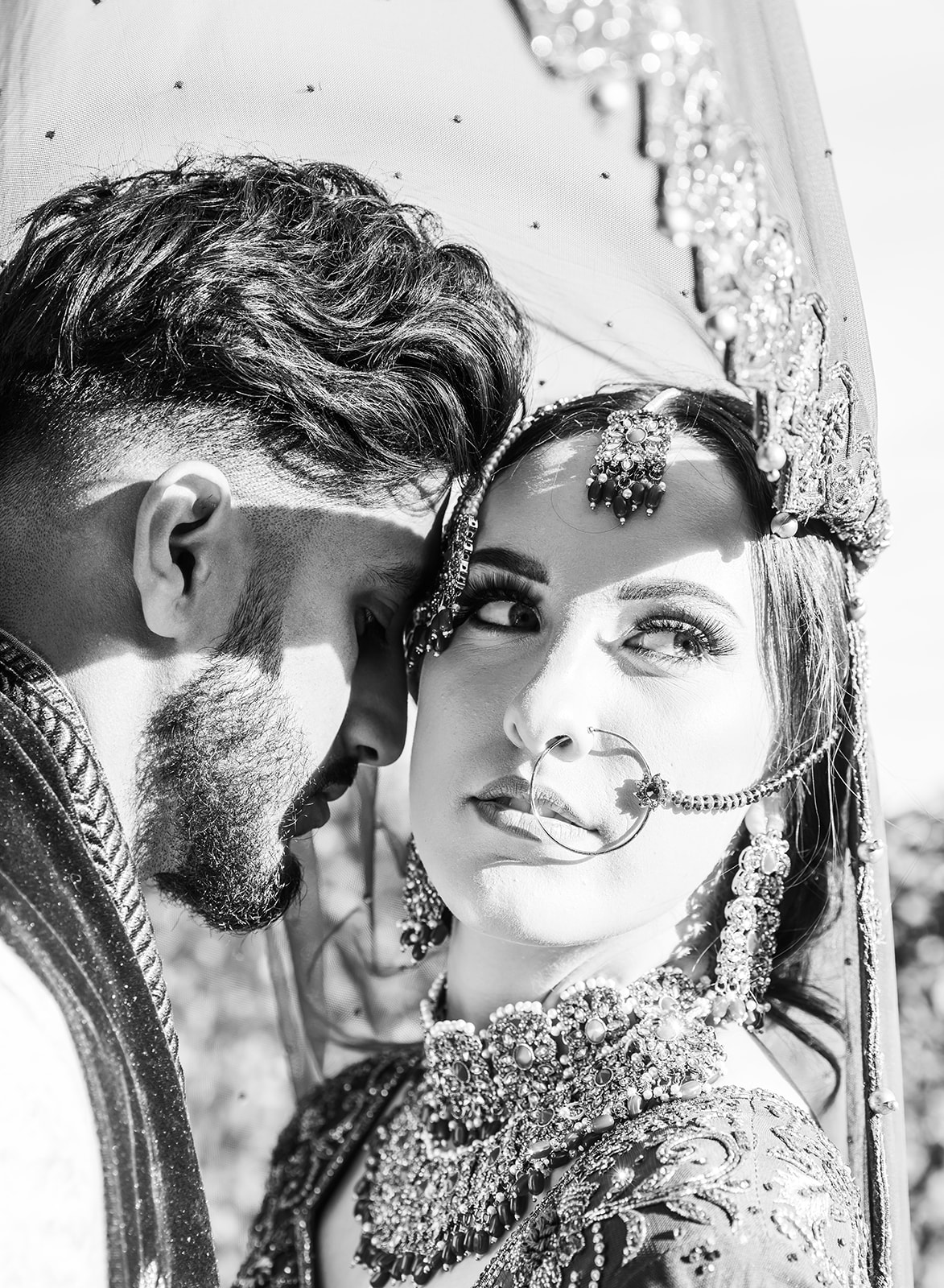 Close-up black and white portrait of a South Asian bride and groom in Gloucester, highlighting the intricate bridal jewelry and veil against a bright, high-contrast background.