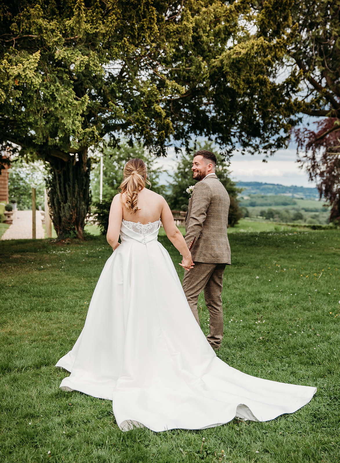 Bride and groom walking through the grounds of Bredenbury court barns for couple photos in the malverns