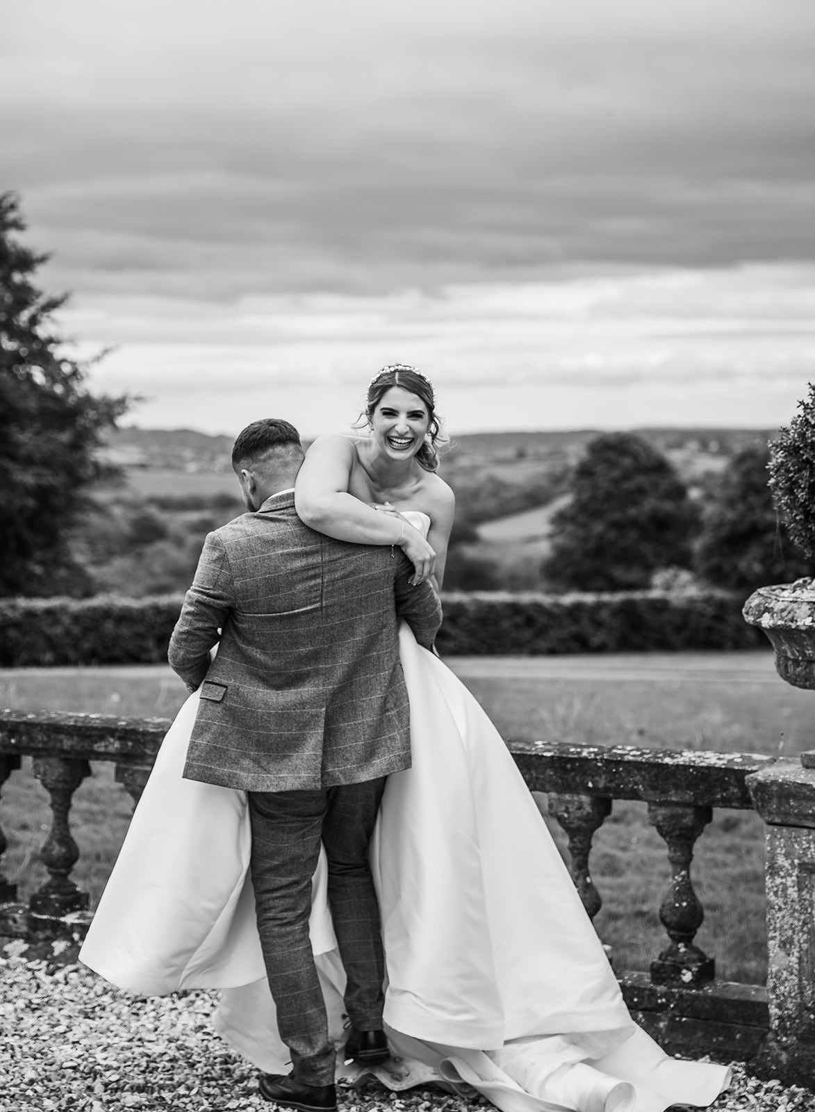 Bride laughing over grooms shoulder, happy black and white candid image at bredenbury court barns