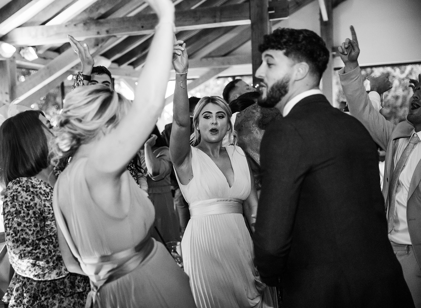 People in wedding attire dancing at bredenbury court barns wedding reception, black and white candid image