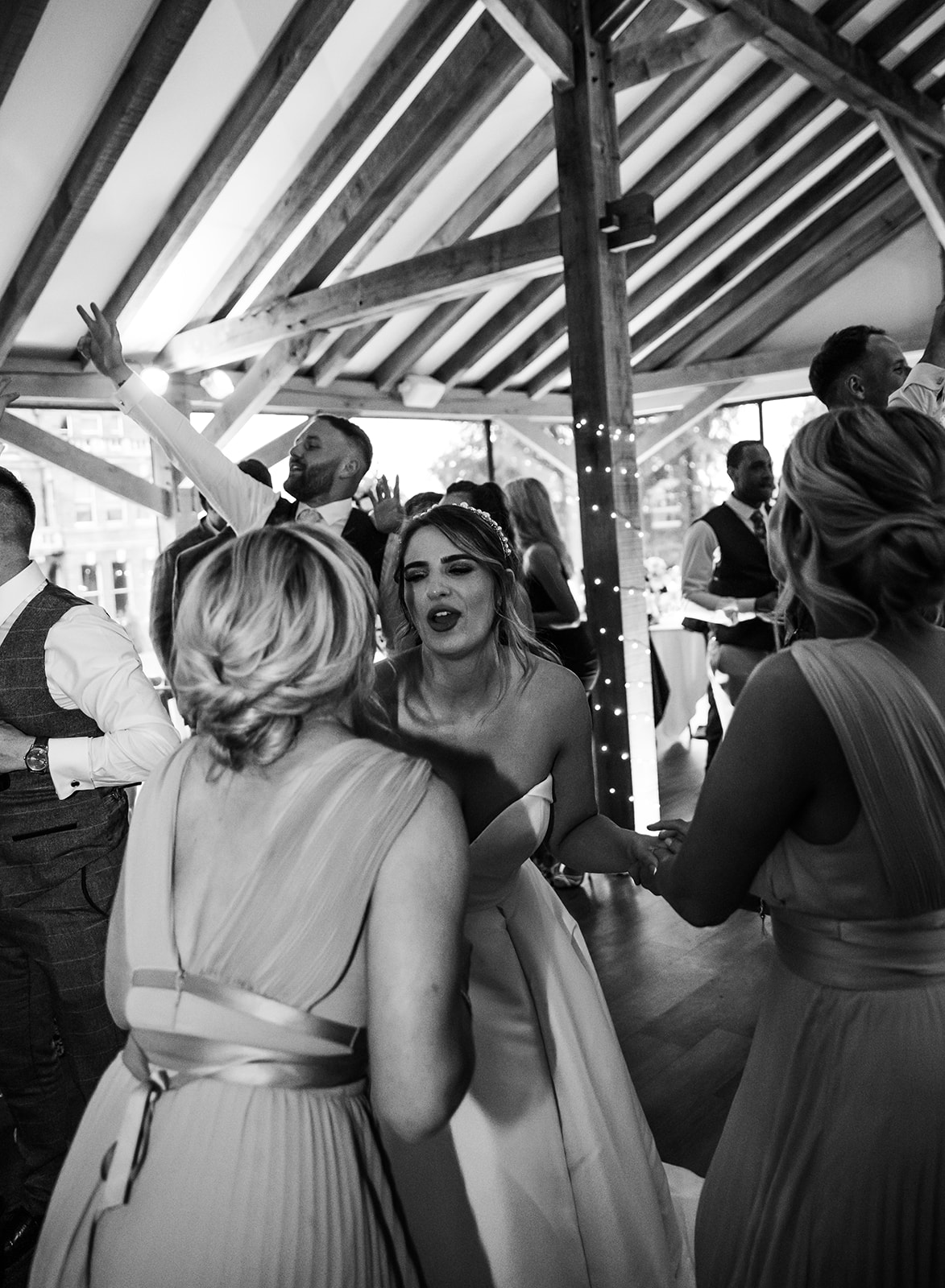 Bride at bredenbury court barns dancing with bridesmaids in black and white candid photo