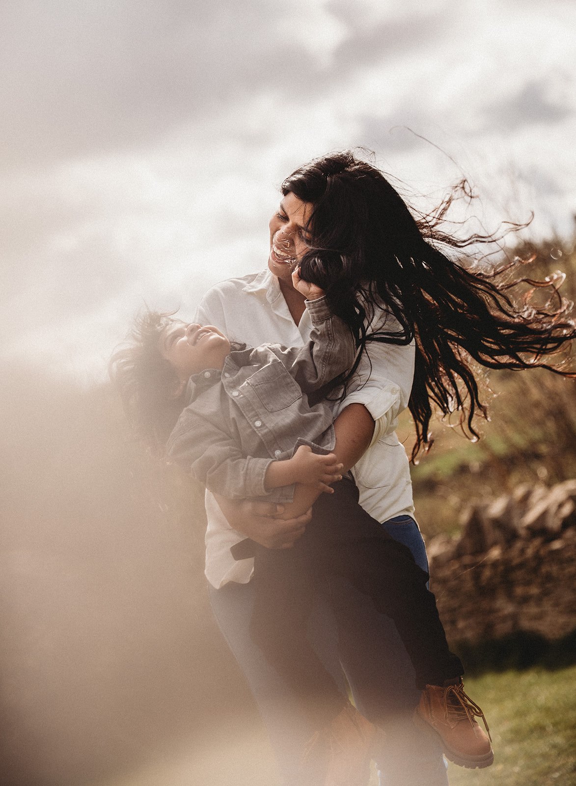mother and son dancing on top of crickley hill in the cotswolds